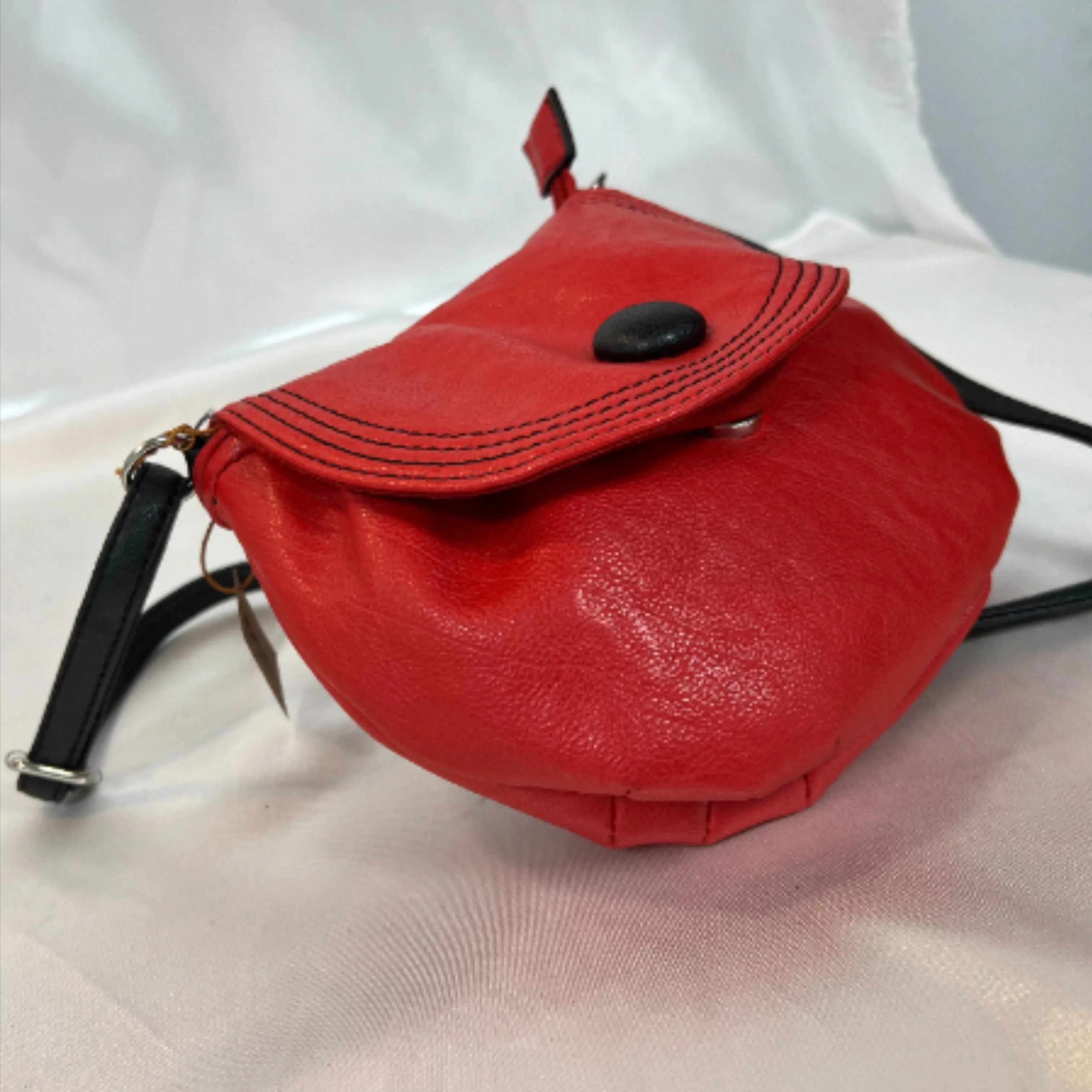 sac modèle le messager. En simili cuir, en rouge et une sangle noire. Chic, original, au format arrondi avec rabat orné d'u